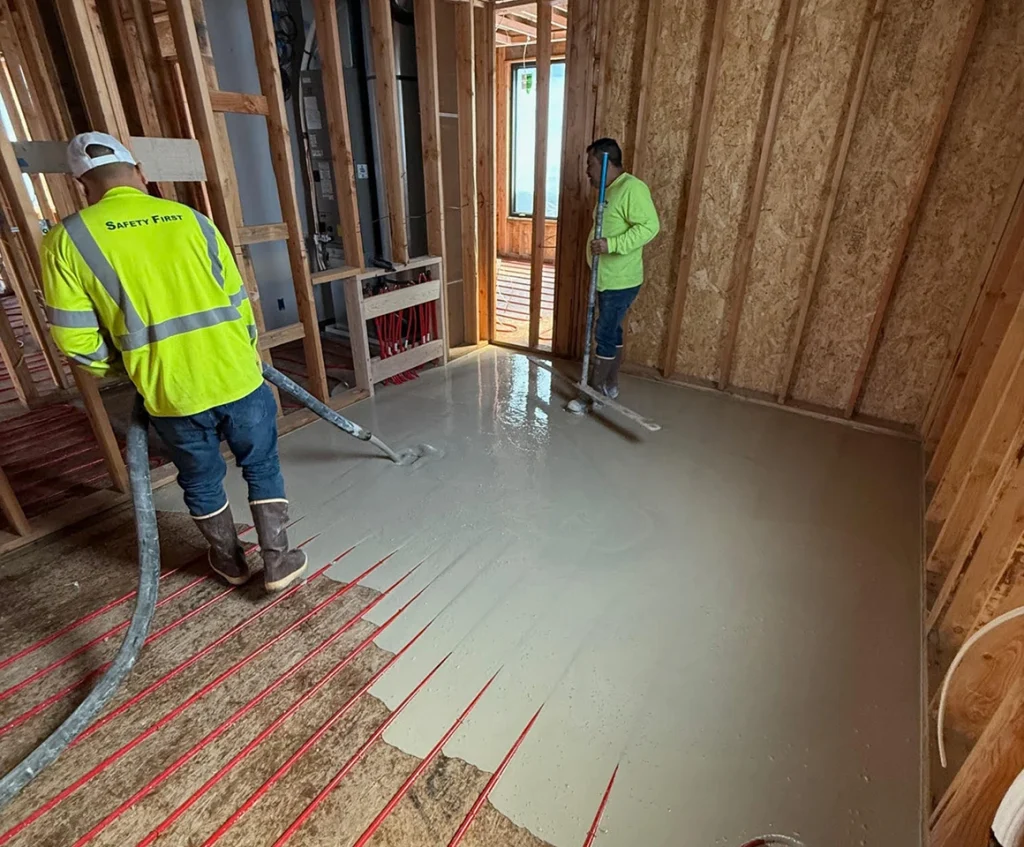 Workers installing radiant heat topping slab over red heating tubes